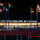 夜の大阪関西万博西ゲート。各国の国旗がはためいている。
