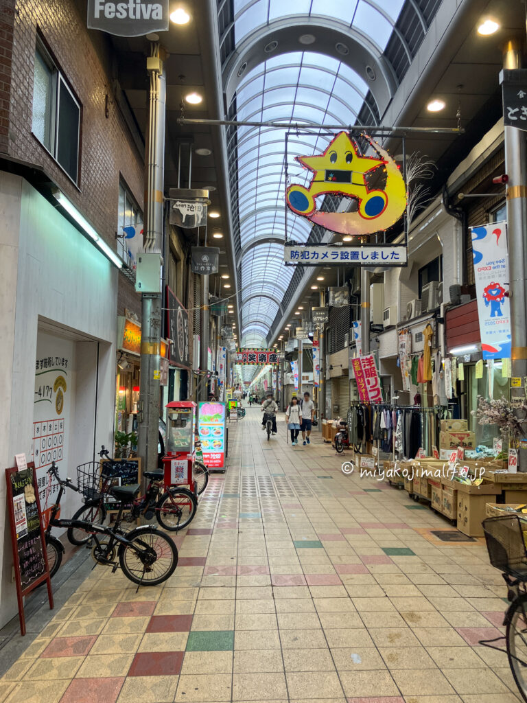 飲食店や洋服屋さん、八百屋さんなどがあるアーケード商店街。頭上にはマスコットのような星と三日月のマーク。